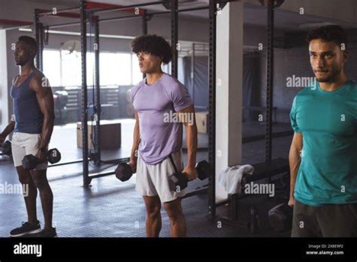 Kyo busy lifting weights while standing in a grey shirt